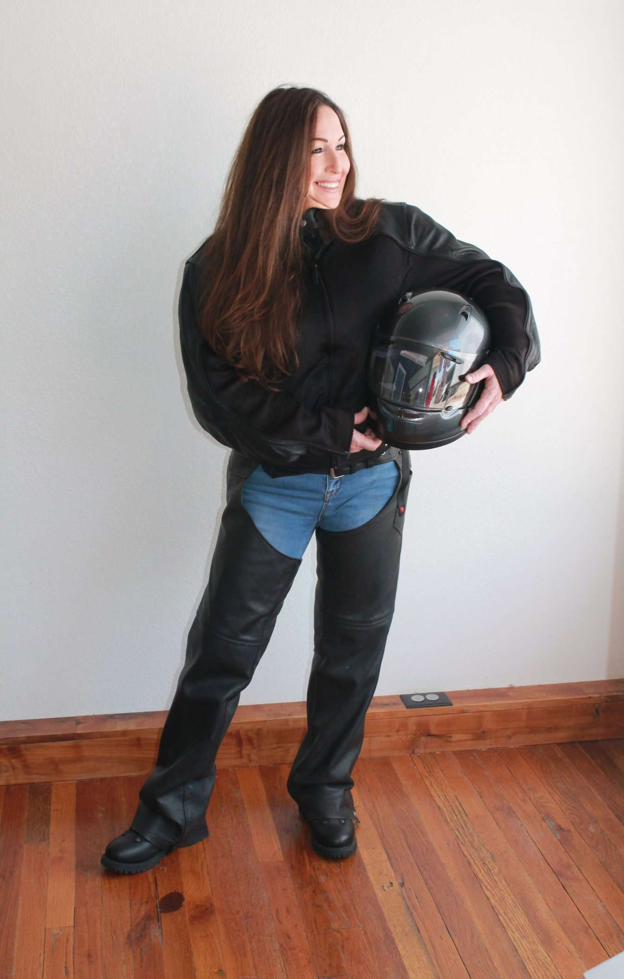 Lisa Lunsford standing in motorcycle riding gear, holding her helmet.