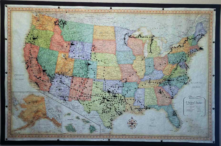 A framed United States map marked with pins tracing Lisa's cross-country motorcycle route through resort towns and national parks.